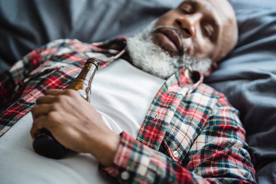 Image illustration of a person sleeping with alcohol bottles around, depicting the impact of alcohol on REM sleep.