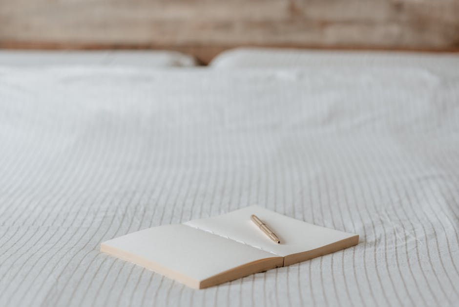 A picture of a person sleeping with a notebook and pen beside them.