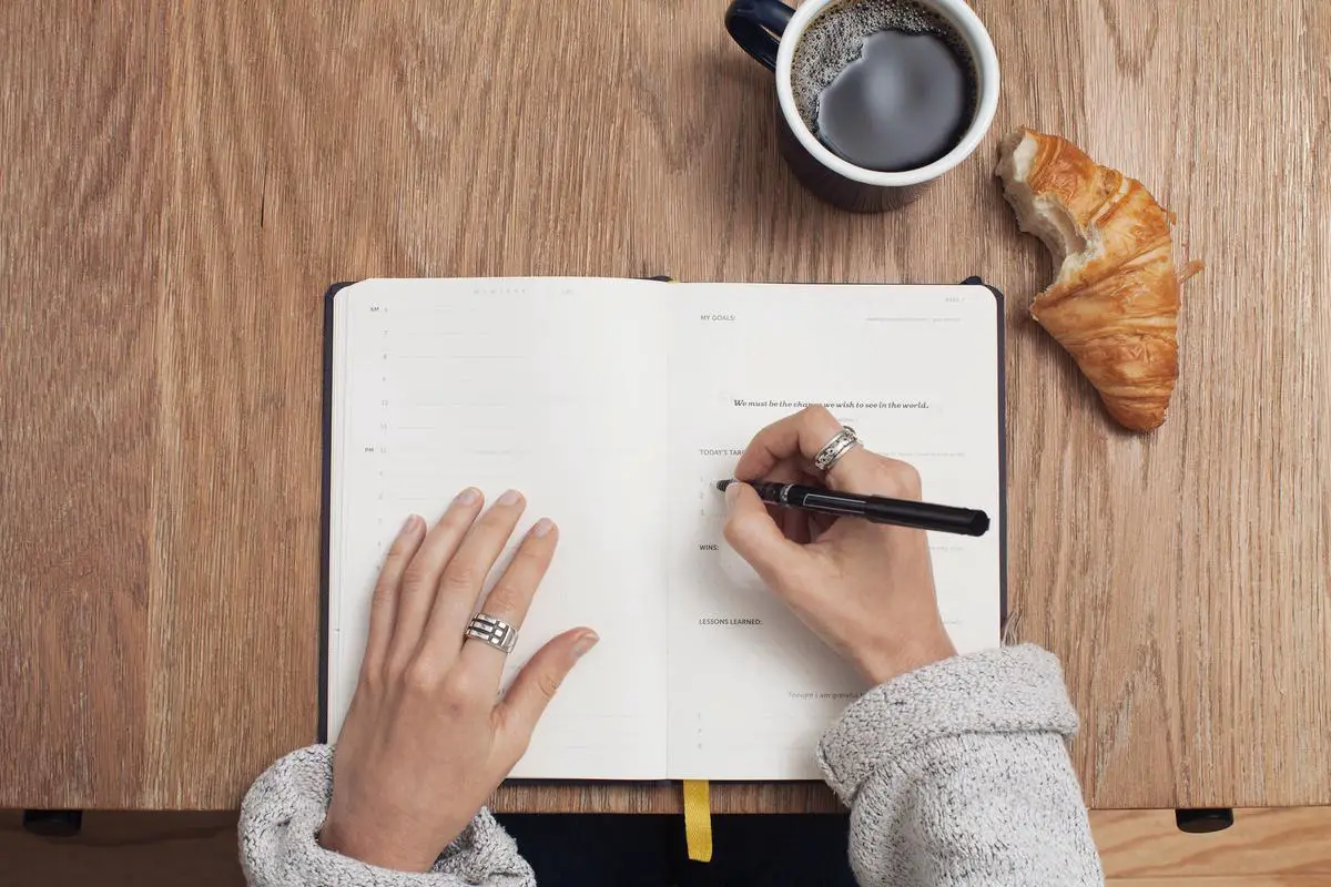 An image of a person holding a notebook and writing in it, symbolizing dream recollection and journaling.