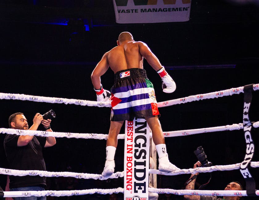 A person standing triumphantly over a defeated opponent in a boxing ring.