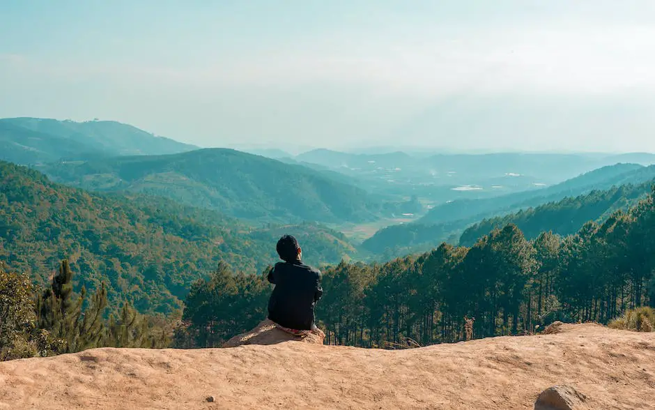 A person is sitting on the edge of a cliff and staring into the horizon with a worried expression on their face. The image signifies the fear of falling or failing.