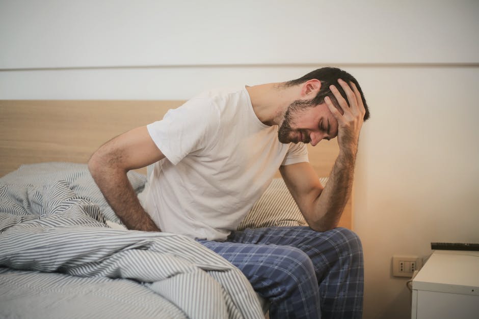 a person laying in bed with their hand on their neck, seemingly in distress