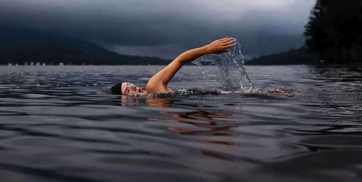 Image of a person swimming with determination against a current, representing the struggle and perseverance needed to overcome challenges.